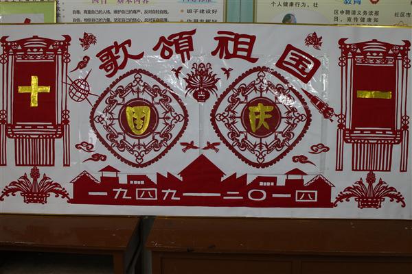 为迎国庆,共贺祖国65华诞,无锡市南长区金星街道翠园社区老年大学剪纸班的老人经过集体创作、分工协作,耗时一周,专门制作了一幅以国庆为主题的大型剪纸作品《歌颂祖国》。在火红的灯笼照耀下,窗花、祥云、白鸽、高楼、卫星、火箭,一个个生动的剪纸图案,仿佛在讲述祖国65年来的光辉历程,讴歌了人民美好的生活,社会的和谐稳定,祖国的繁荣昌盛。 在翠园社区的一间活动室内,挂满了剪纸班老人们的剪纸作品,有的作品倡导清正廉洁,有的倡导安全交通出行,有的庆祝五一,有的庆祝党的生日老人们凭着一把剪刀、一把刻刀,从